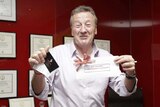 Chris Dawe smiles as he holds up a gift voucher and smiles for a photo.