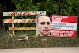 A posted wanted sign for a mass shooting suspect is seen by the roadside.