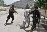 Afghan security forces arrest a man during a clash with insurgents near a peace conference.