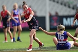 Melbourne's Daisy Pearce (L) handballs as she is tackled by Western Bulldogs' Katie Brennan.
