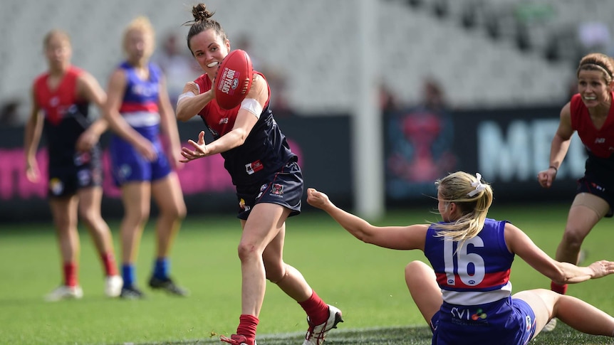 Melbourne's Daisy Pearce (L) handballs as she is tackled by Western Bulldogs' Katie Brennan.