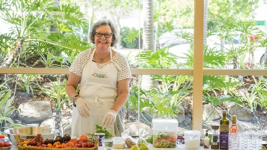 Alison Alexander standing at a table in front of ingredients preparing a dish