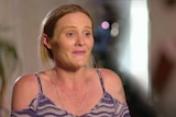 Emma Broughan sitting in her home wearing a silver necklace and a purple patterned top