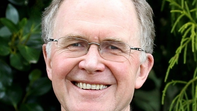 A man in glasses smiles into the camera