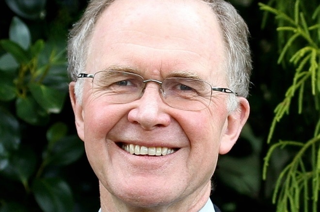 A man in glasses smiles into the camera