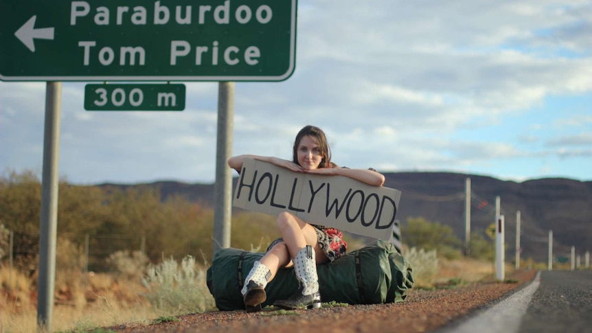 Kara Lauder on the side of the road with a Hollywood sign.