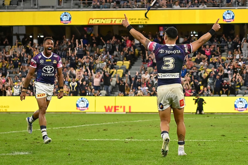Valentine Holmes raises both hands as Cowboys teammate Hamiso Tabuai-Fidow runs to him smiling after beating the Tigers.
