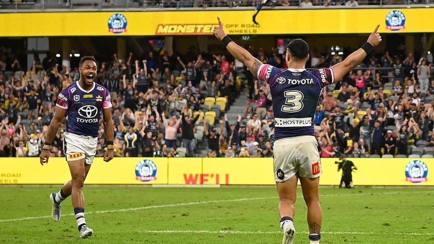 Valentine Holmes raises both hands as Cowboys teammate Hamiso Tabuai-Fidow runs to him smiling after beating the Tigers.