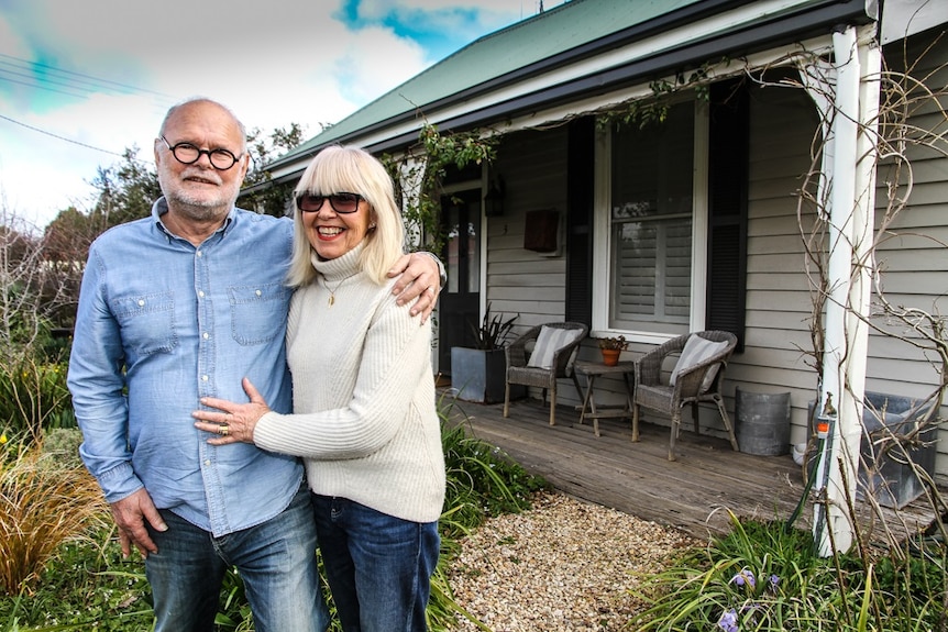 An older couple standing outside a house in regional Victoria