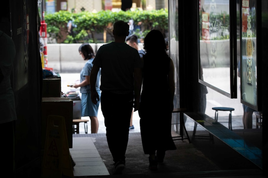 The silhouette of a couple holding hands and walking together in a covered walkway Hong Kong.