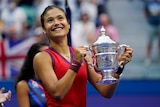 Britain's Emma Raducanu has a beaming smile as she holds the US Open trophy with both hands.