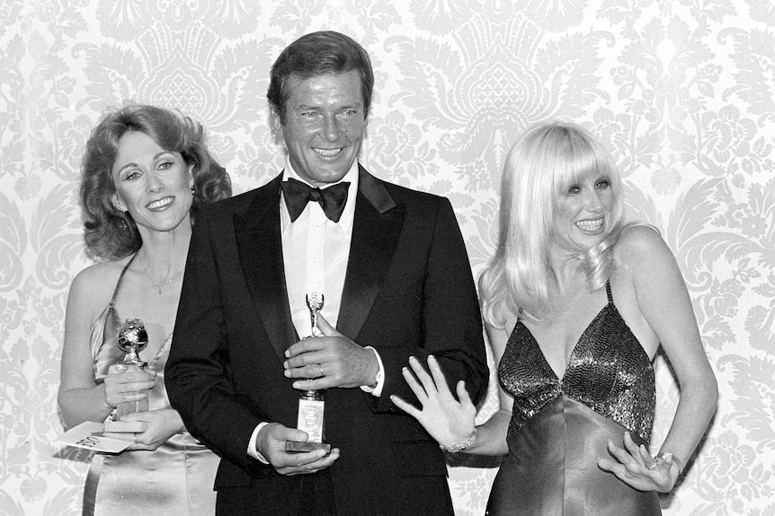 a black and white photo of three people dressed up with golden globe awards
