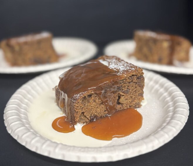Apple and spice tray bake with caramel sauce, cream, and icing sugar. 