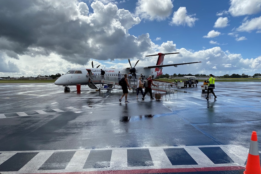 Gente caminando por la pista para subirse a un avión.