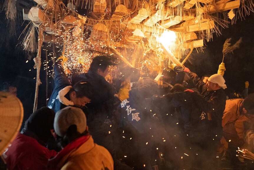 Japanese men attach a wooden structure with flames during the Nozawa Onsen Fire Festival