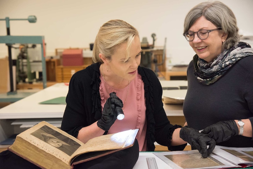 Maggie Patton and Rachel Spano inspect a book