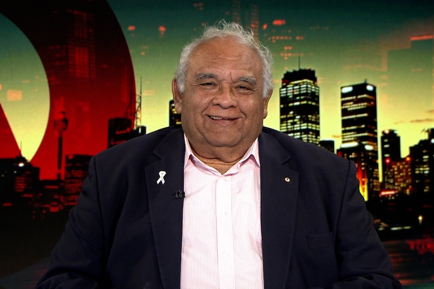 Man in a suit smiling while on a panel show. 