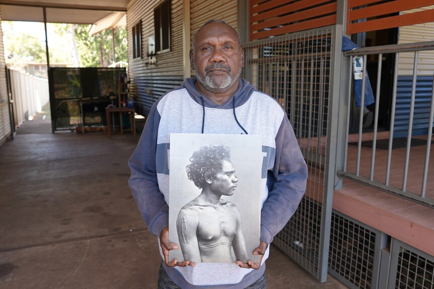 A man holding up a black and white image of Dirrikaya