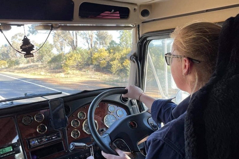 Looking over the shoulder of a woman as she drives a truck