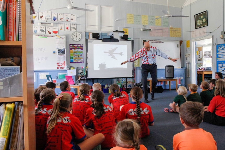 Students sit in a classroom listening to Dr Karl explain how planes work.