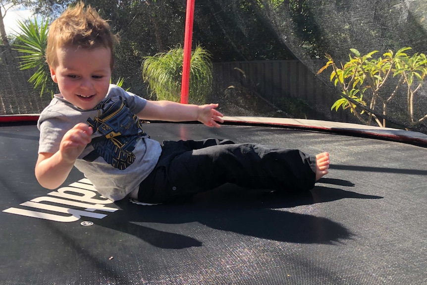 A young boy bounces on a trampoline.