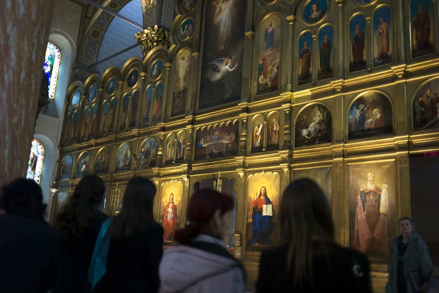 Serb women stand before the ornate Iconostasis in Sarajevo's Orthodox cathedral, rebuilt after the war.