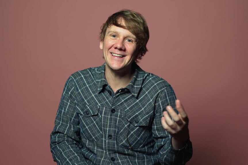 Josh Thomas in front of pink background