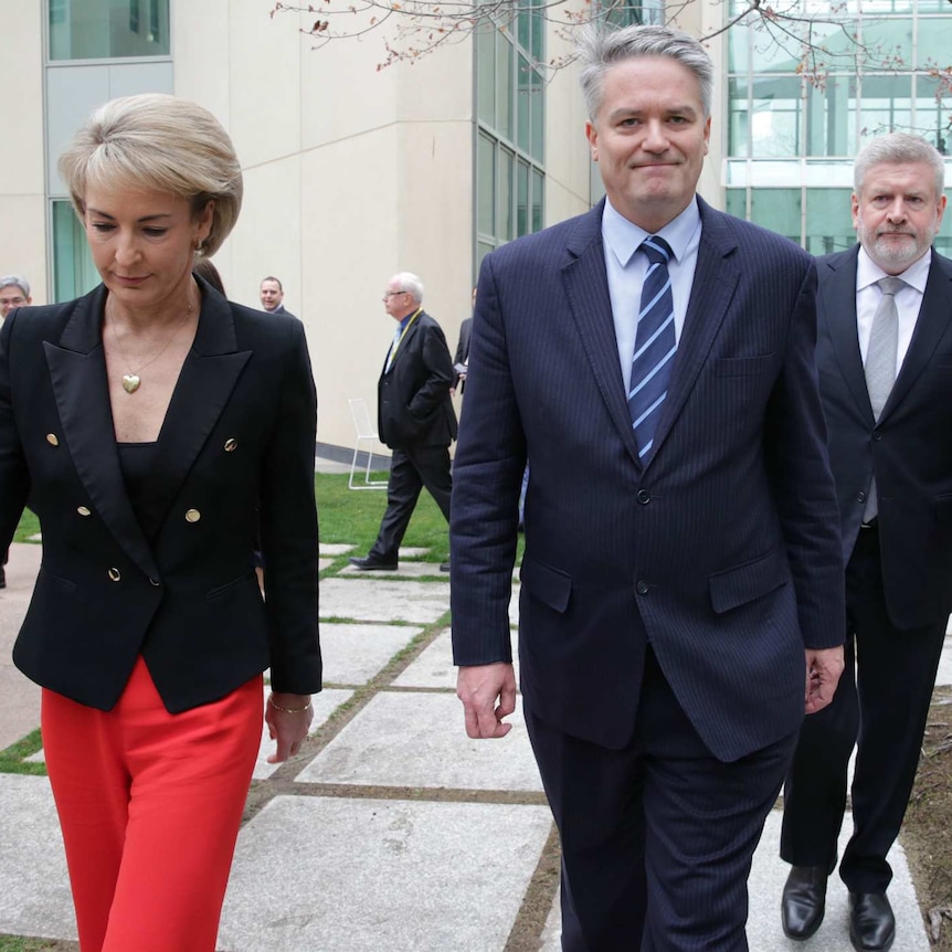 Mathias Cormann, flanked by Michaelia Cash and Mitch Fifield, walk outside Parliament