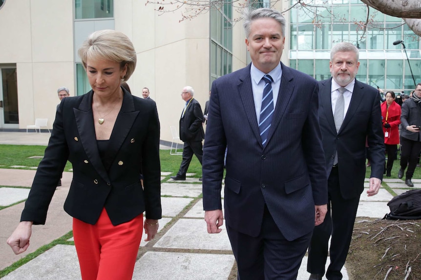 Mathias Cormann, flanked by Michaelia Cash and Mitch Fifield, walk outside Parliament