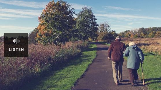 Photo of two elderly people walking along a country road . Has Audio.