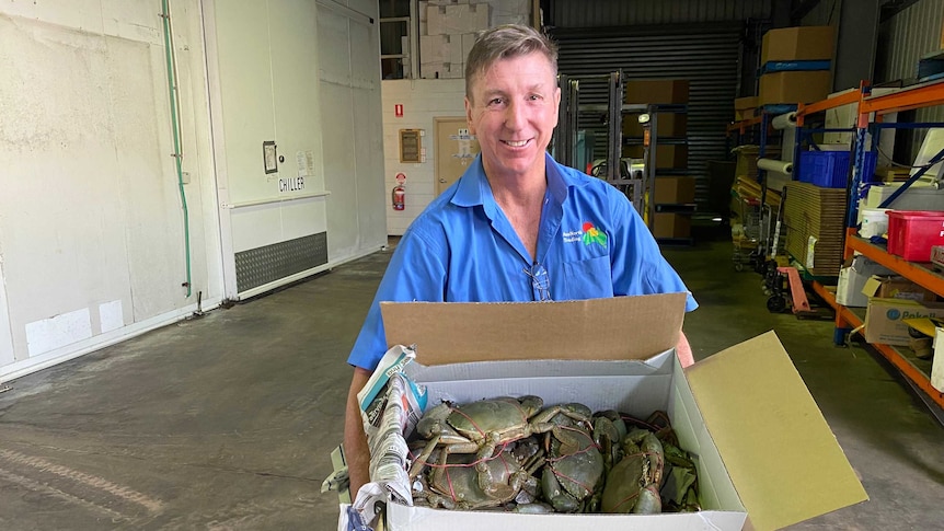 a man holding a box of mud crabs.