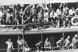 Black and white photo showcases people crowded onto a boat