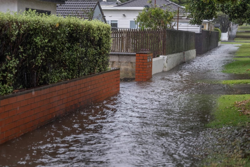 A footpath outside homes is covered in water.