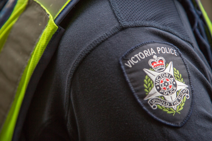 A close up of a police badge on a uniform, says Victoria Police, Uphold the rights.