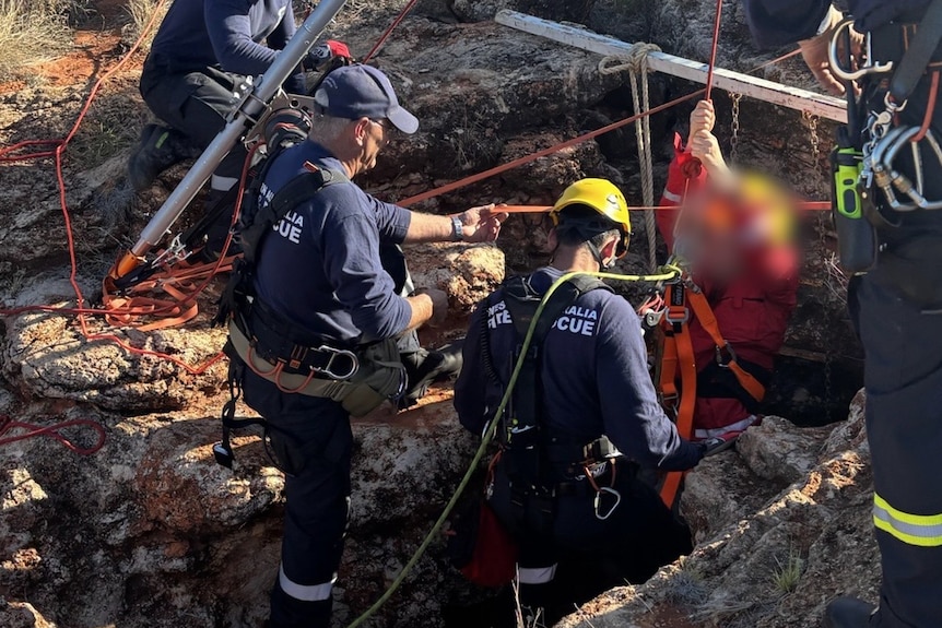 A fire engine and emergency services personnel work to free a woman from a cave.