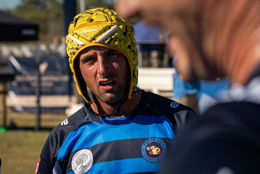 Joe Bode, a local player, stands facing his coach