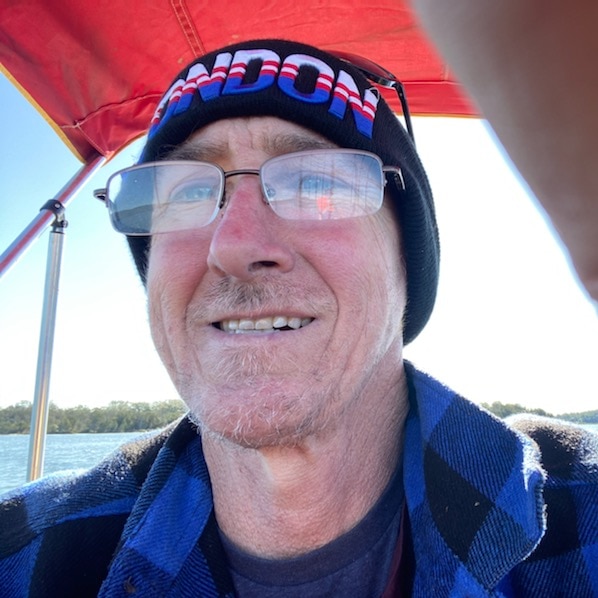 Stephen smiles, wearing a beanie and glasses. It's a selfie and it looks like he's on a boat.