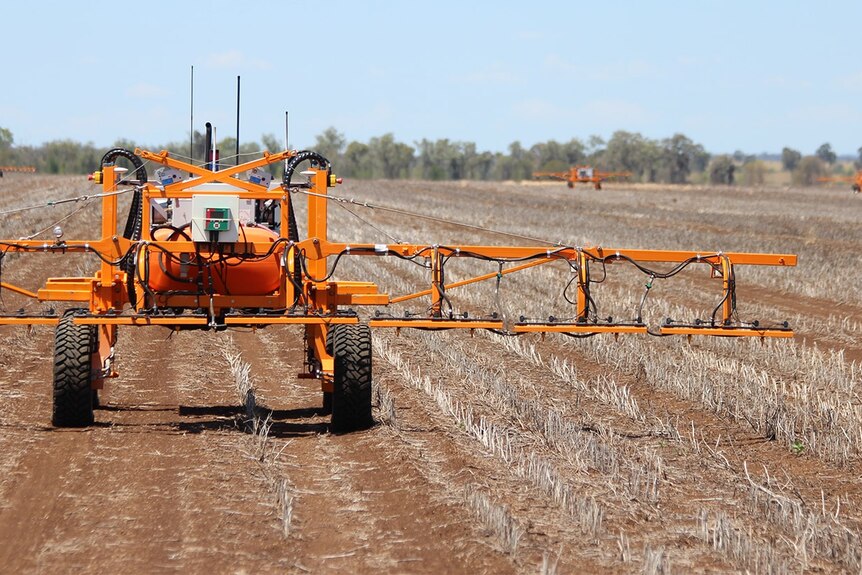 An orange robot sprayer in a field.