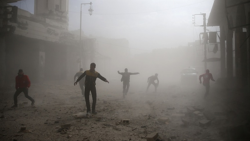 People run through a dusty street after an air raid.