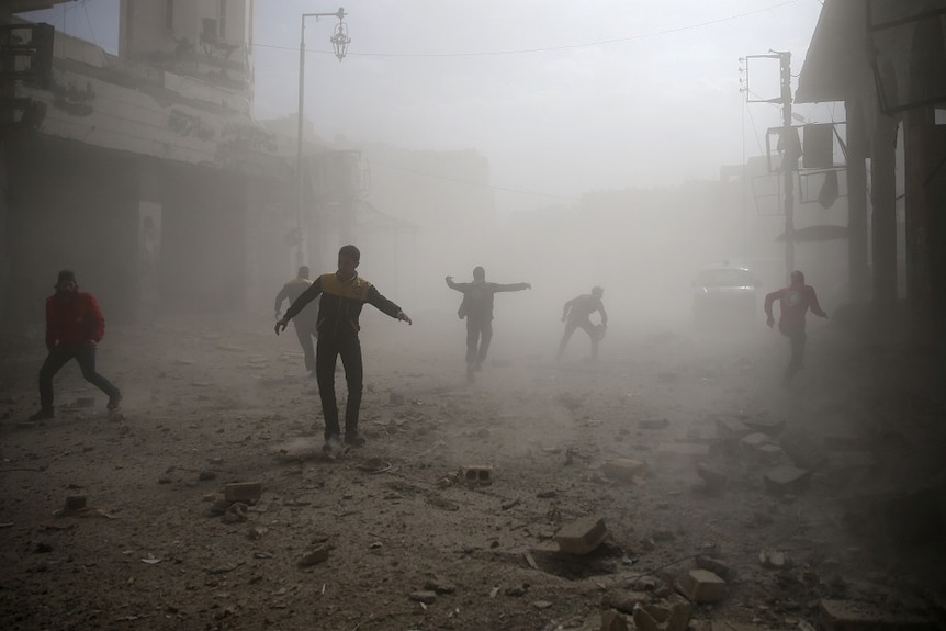 People run through a dusty street after an air raid.