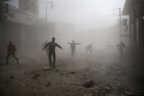 People run through a dusty street after an air raid.