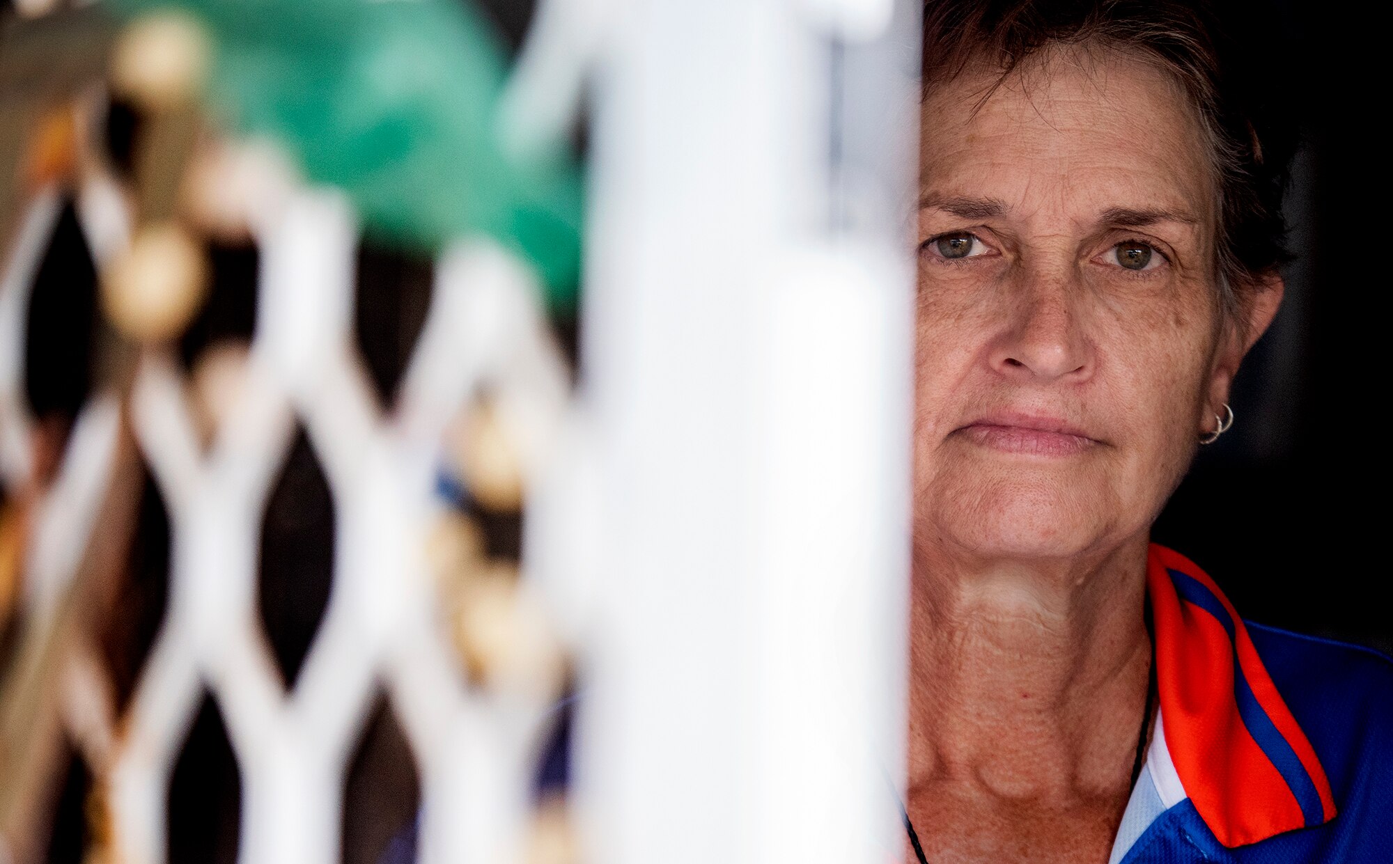 A woman peaks out of a screen door.