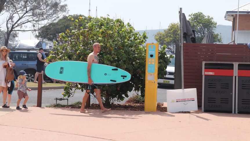 Surfer near sunscreen vending machine