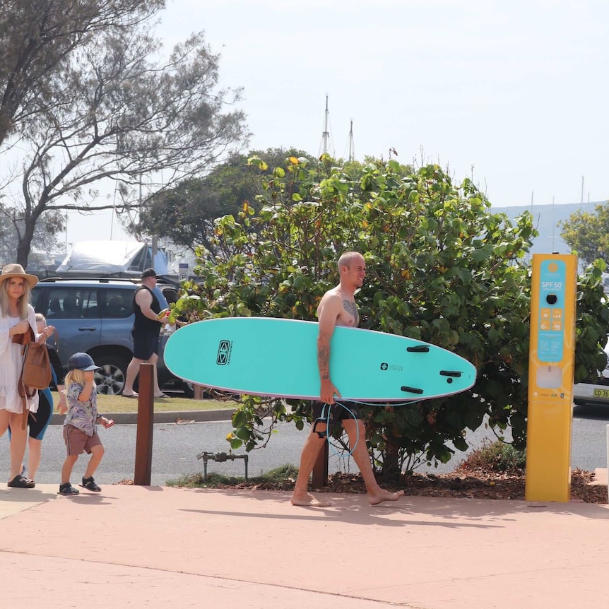 Surfer near sunscreen vending machine