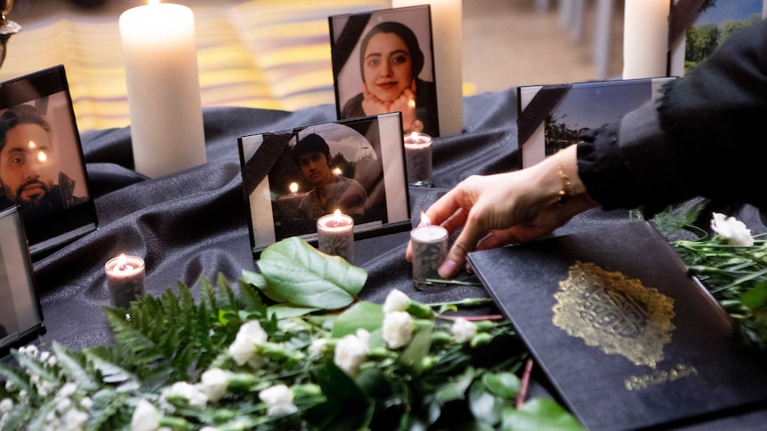 A candle is placed in front of a photo of a woman in a vigil.