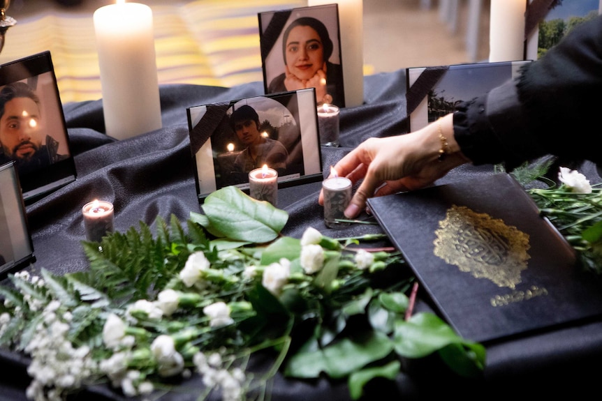 A candle is placed on a table bearing photos of some of the victims of a plane crash.