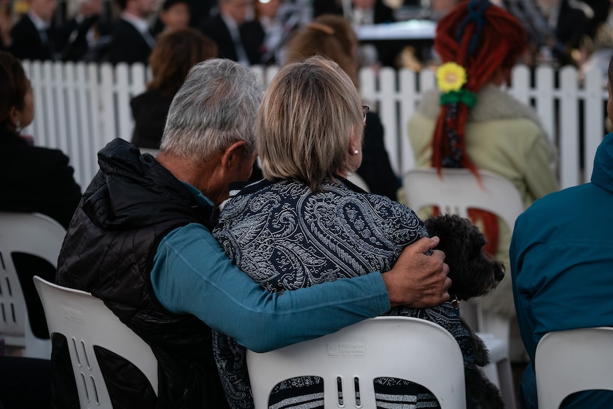 a couple hug while sitting down at Bondi Beach vigil 210424