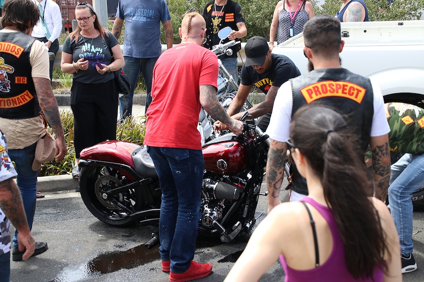 Bandidos members help lift a bike involved in an incident.