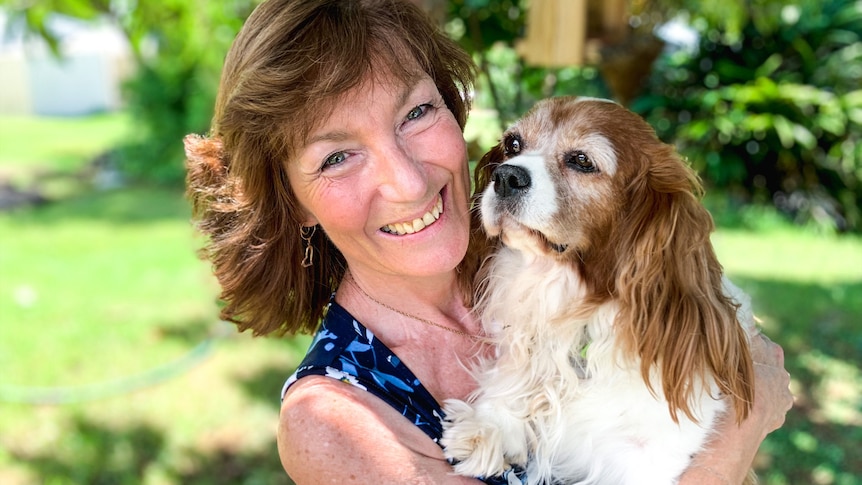 A smiling woman holds a spaniel