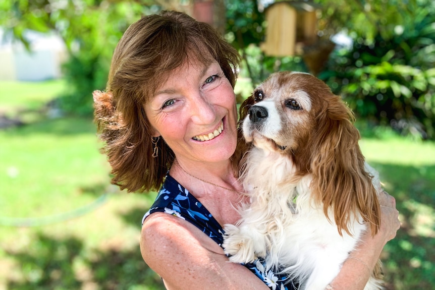 A smiling woman holds a spaniel